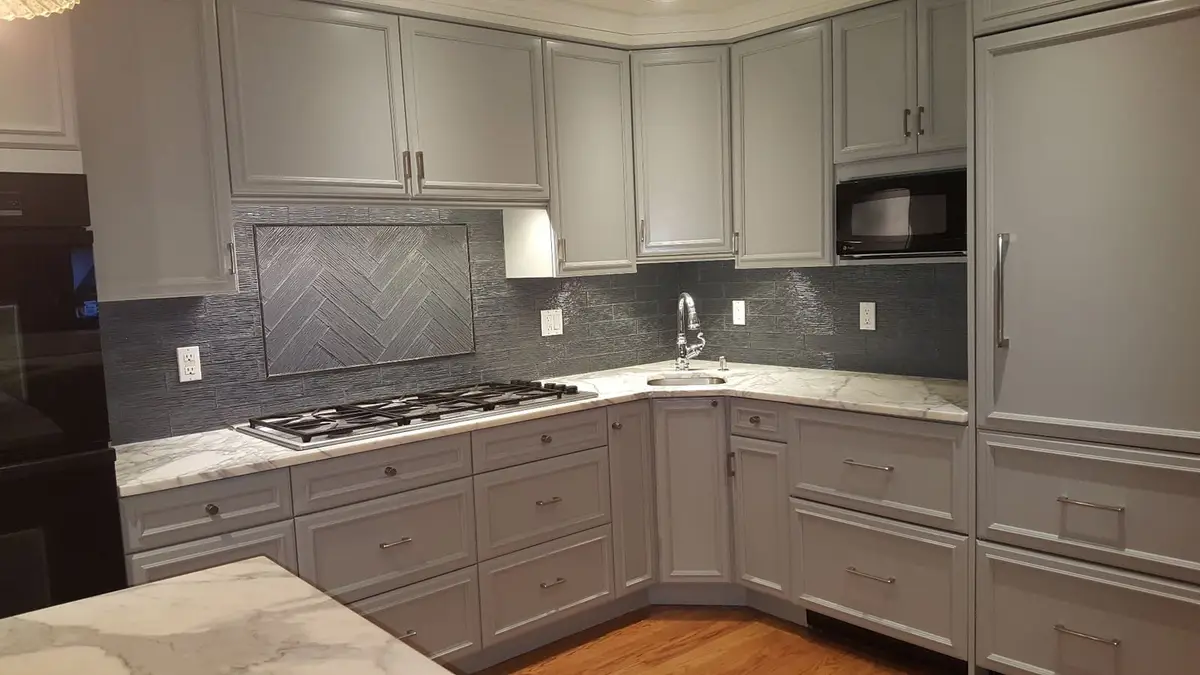Glass Herringbone — Elegant glass tile backsplash in classic herringbone pattern with decorative picture frame border detail